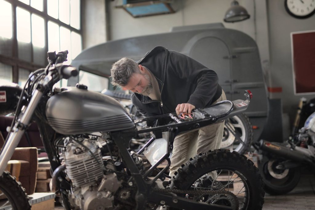 man in black jacket inspecting a motorcycle