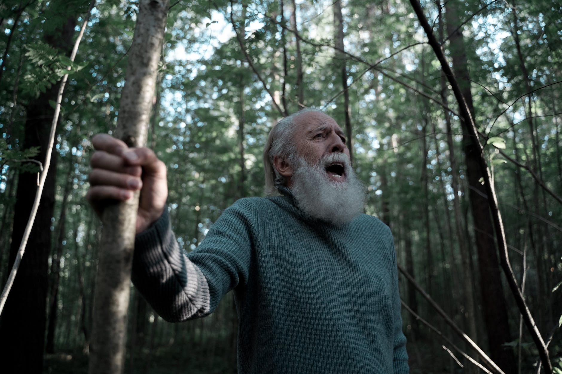 man in turtleneck sweater shouting in forest