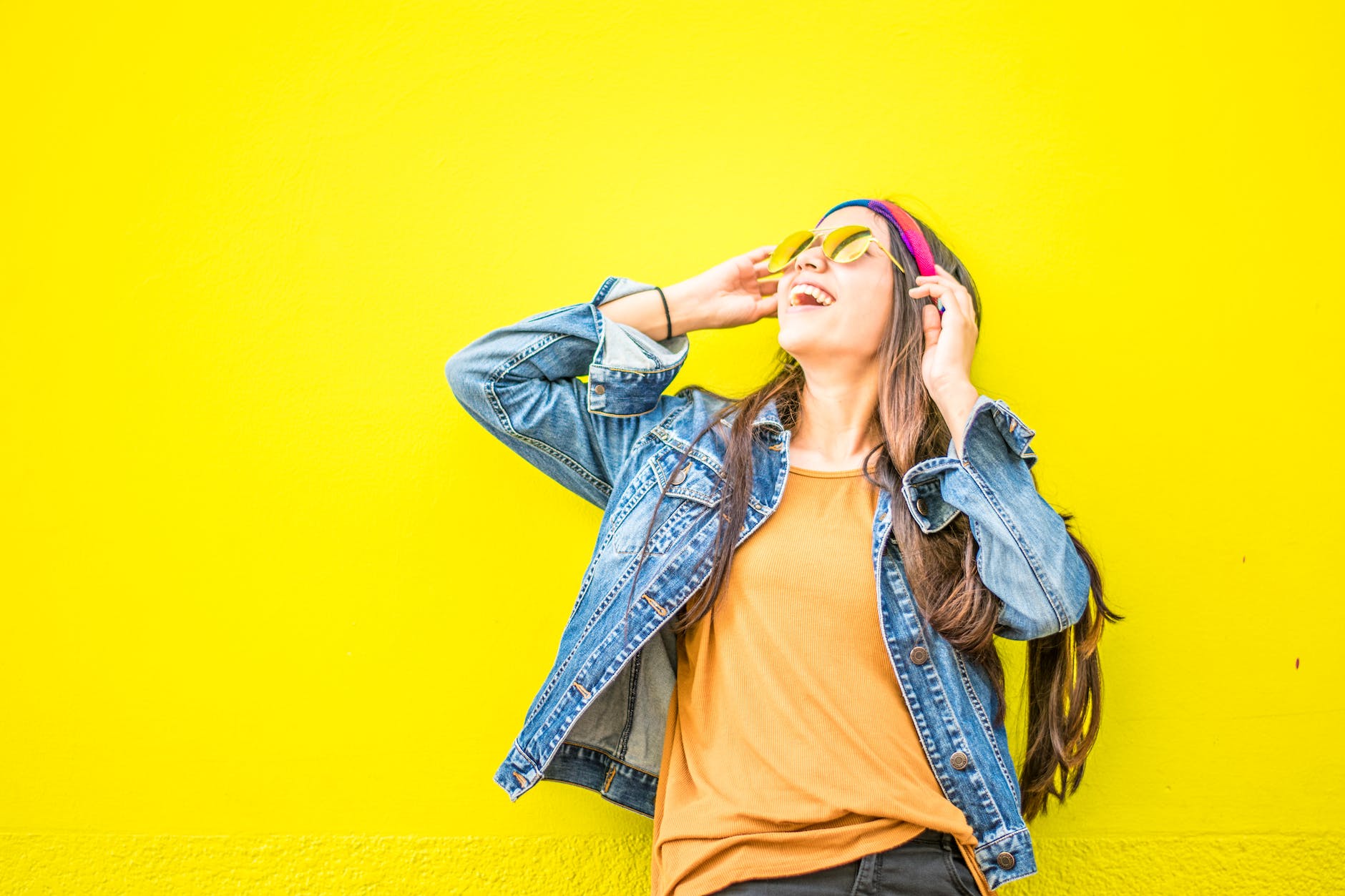 smiling woman looking upright standing against yellow wall