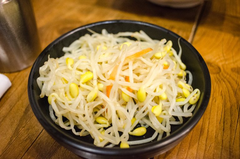 cooked bean sprouts on a black bowl