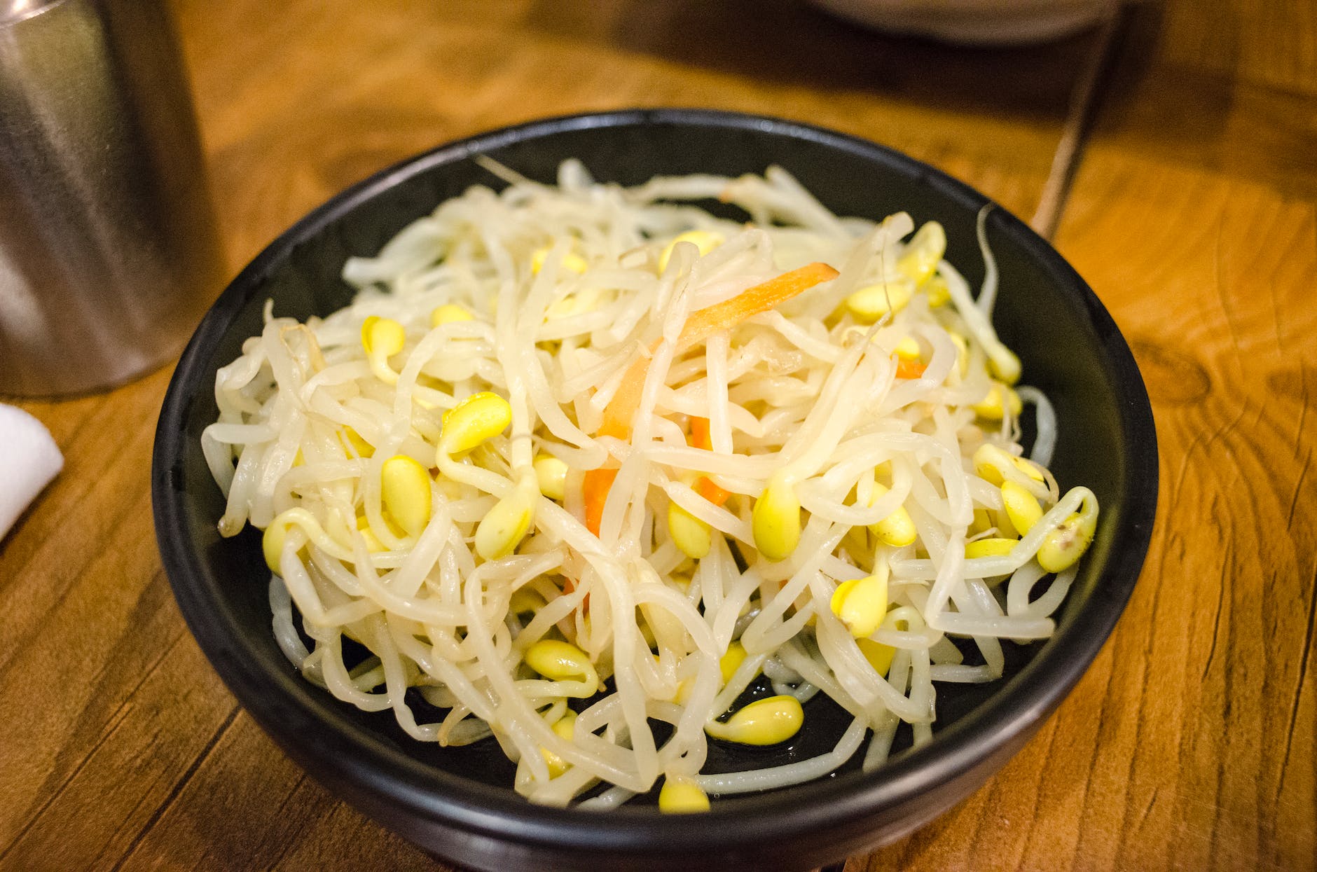 cooked bean sprouts on a black bowl