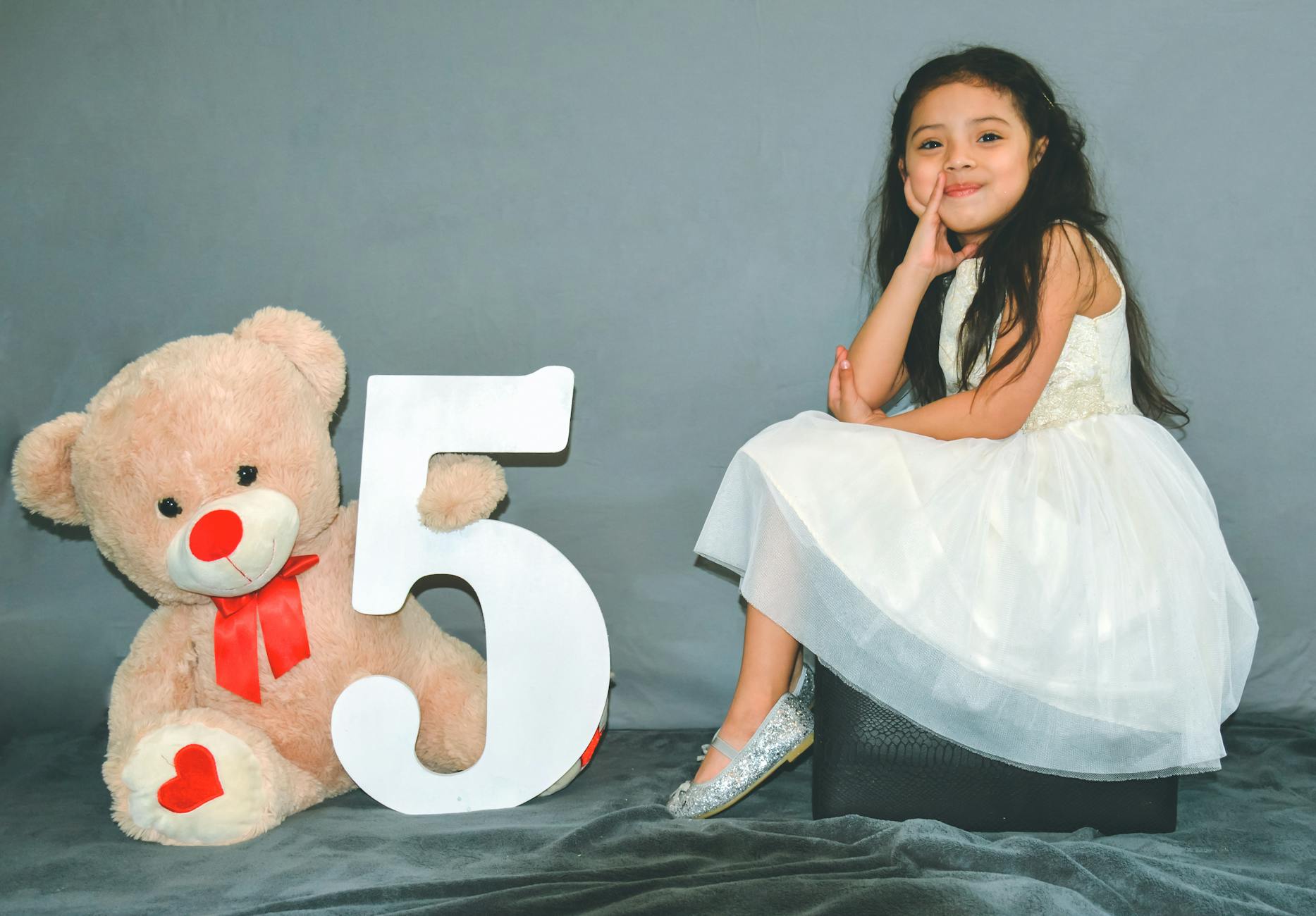 girl sitting beside bear plush toy